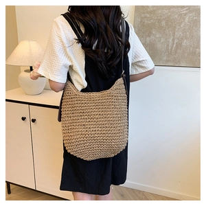 Detailed texture of handcrafted woven straw hobo bag with brown leather shoulder strap