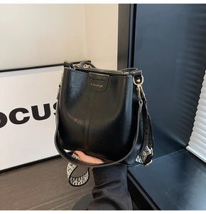 Close-up of black PU leather bucket bag with black and white geometric woven strap