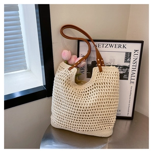 Detail of hollow woven tote bag featuring beige mesh fabric and brown leather handle