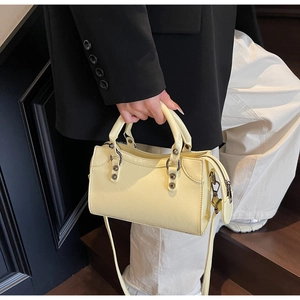 Détail d'un sac à main jaune pâle texturé avec des rivets vintage et des ferrures
