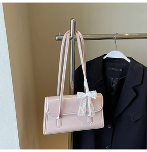 Détail du sac à bandoulière en cuir verni rose clair avec nœud en dentelle blanche