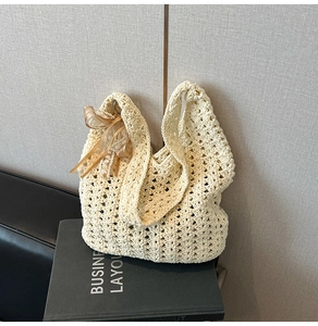 Détail d'un sac cabas en crochet beige orné d'un ruban doré translucide élégant