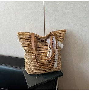 Close-up of woven straw tote bag featuring white lace ribbon and beaded charm detail