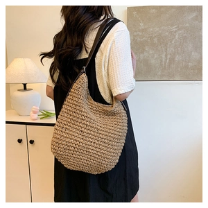 Close-up of a handmade woven straw hobo bag with slim brown leather strap