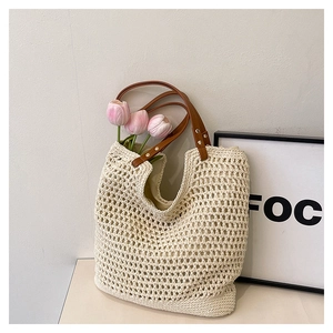 Close-up of the beige hollow knit tote bag with brown leather handles and mesh weaving
