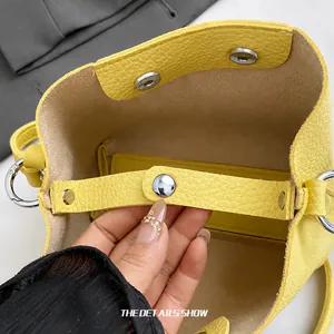 Gros plan sur le fermoir magnétique argenté et la doublure en daim du sac jaune