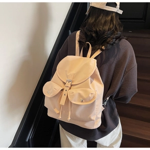 Chic beige nylon backpack featuring flap closure and twin front pockets on stairs