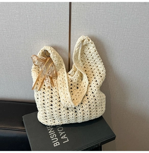 Détail d'un sac cabas en crochet crème avec motifs ajourés et charmant nœud en soie