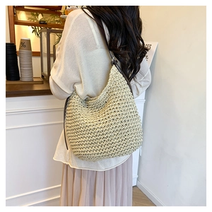 Detail of woven straw hobo bag with dark straps showing grid texture and large capacity