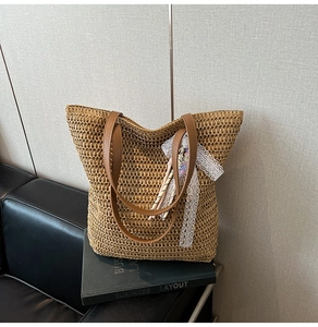 Close-up of woven straw tote bag with brown leather straps and floral lace detail