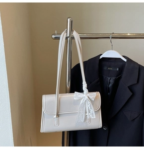 Détail du sac à bandoulière crème brillant avec un charmant nœud en dentelle délicate