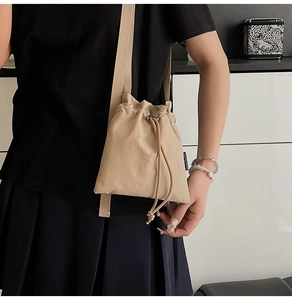 Detail of khaki nylon bucket bag with drawstring closure and silver adjustable metal buckle