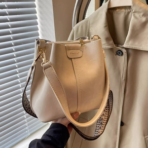Detail of cream bucket bag with vintage woven wide strap and sleek leather texture