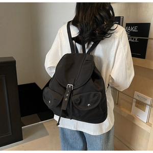 Detail of black nylon backpack with silver buckle closure and dual front flap pockets