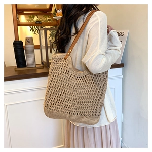 Close-up of handmade straw tote bag with brown leather straps and woven mesh texture