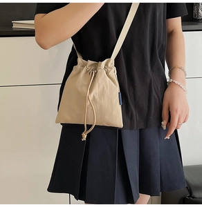 Detail of beige drawstring crossbody bag in pleated high-density fabric with blue tag