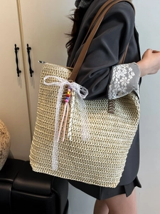 Large woven straw tote bag with brown leather straps and lace bow for beach or daily use