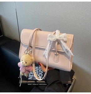 Vue détaillée du sac en cuir verni rose avec nœud en dentelle blanche et ours peluche