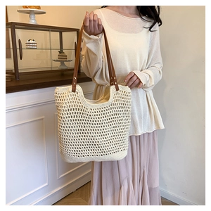 Detail of crochet straw tote bag showing brown leather straps and woven texture