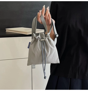 Detail of grey nylon drawstring shoulder bag with pleated texture and adjustable strap