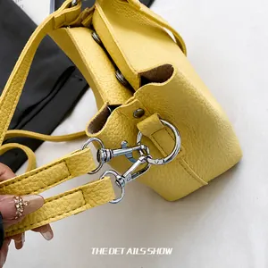 Détail du crochet en métal argenté et texture du cuir jaune grainé du sac seau
