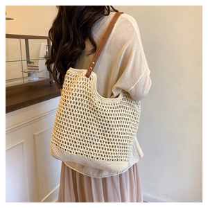 Detail view of woven beige tote bag with brown leather straps and mesh texture