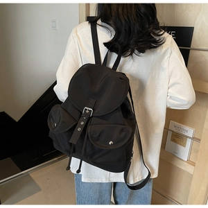 Close-up of black nylon backpack featuring silver metal buckles and drawstring closure