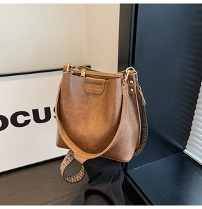 Close-up of caramel brown bucket bag with textured wide jacquard shoulder strap