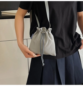 Detail view of light grey nylon bucket bag with NINGNING brand label and drawstring