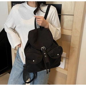 Close-up of black nylon backpack with silver buckle flap and two front utility pockets