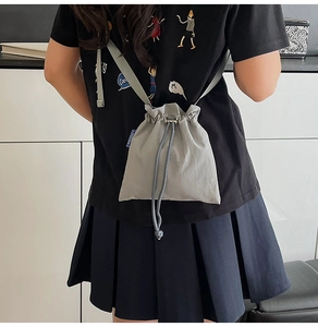 Detailed close-up showing the drawstring closure and pleated nylon fabric of this gray bag