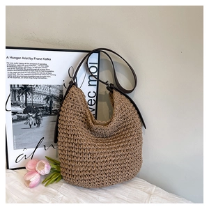 Detail of hand-woven straw bucket bag with dark brown leather strap and silver buckle