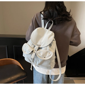 Detailed view of grey nylon backpack with drawstring closure and dual front buckle pockets