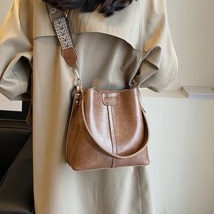 Vintage brown leather bucket bag with decorative stitching and ethnic woven wide strap