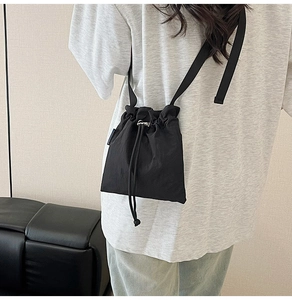 Close-up of black nylon drawstring bucket bag showing adjustable shoulder strap texture