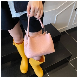 Détail du sac seau rose en cuir à grain litchi avec boucle en métal et logo de mode