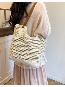 Straw tote bag with hollow diamond knit and brown leather straps worn on shoulder