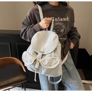 Detail view of stylish light grey backpack with silver metal buckles and drawstring closure