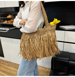 Detail view of woven straw tote bag featuring long fringes and sturdy braided shoulder strap