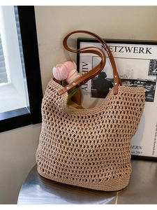 Large woven straw tote bag with brown leather handles for beach and summer travel