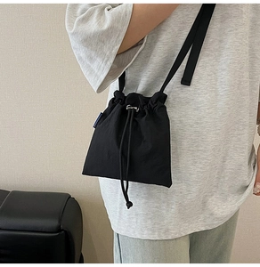Detail of black nylon drawstring bucket bag with pleated texture and adjustable strap