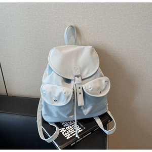 Detail of light blue nylon backpack with silver metal buckles and drawstrings on books
