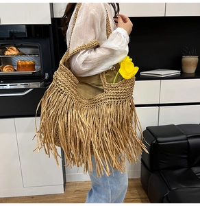 Detailed view of handmade straw tote bag featuring long fringes and bohemian style