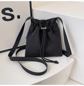Detail view of the black nylon drawstring bucket bag with silver metal cord stopper