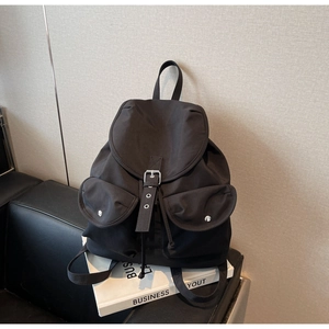 Detail of black nylon backpack with flap closure and dual front buckled pockets
