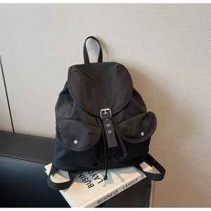 Detail showing the black nylon backpack with silver metal buckles and drawstring closure