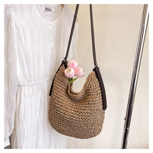 Detail view of woven straw bucket bag with adjustable leather strap and tulip decor