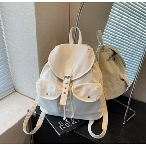 Detailed view of white minimalist nylon backpack with magnetic buckles and drawstring closure