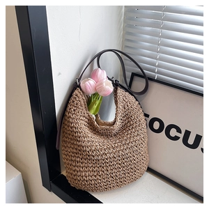 Detail of woven straw bucket bag with dark brown leather strap and pink tulips