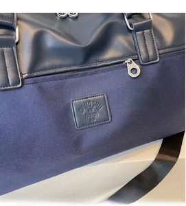 Close-up of dark blue travel bag featuring leather logo patch and silver hardware